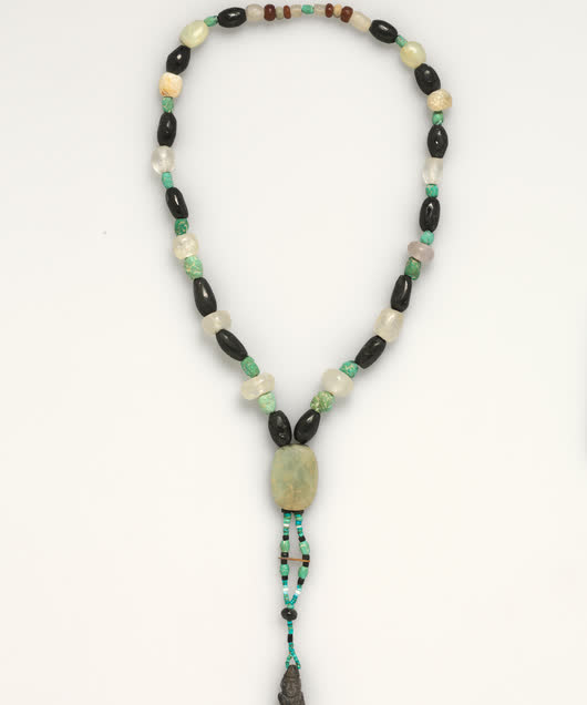 Beaded strand necklace with a carved pendant, studio photograph