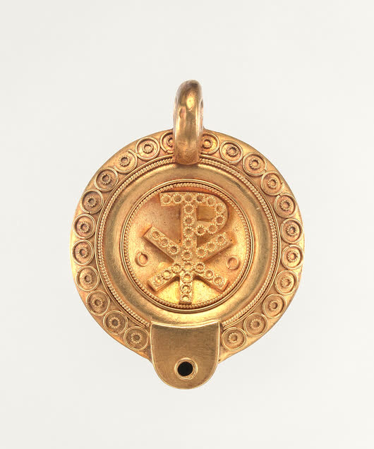 Round gold pendant with a beaded border, studio photograph
